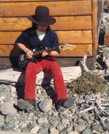 Photo of Sadi Synn playing guitar in front yard